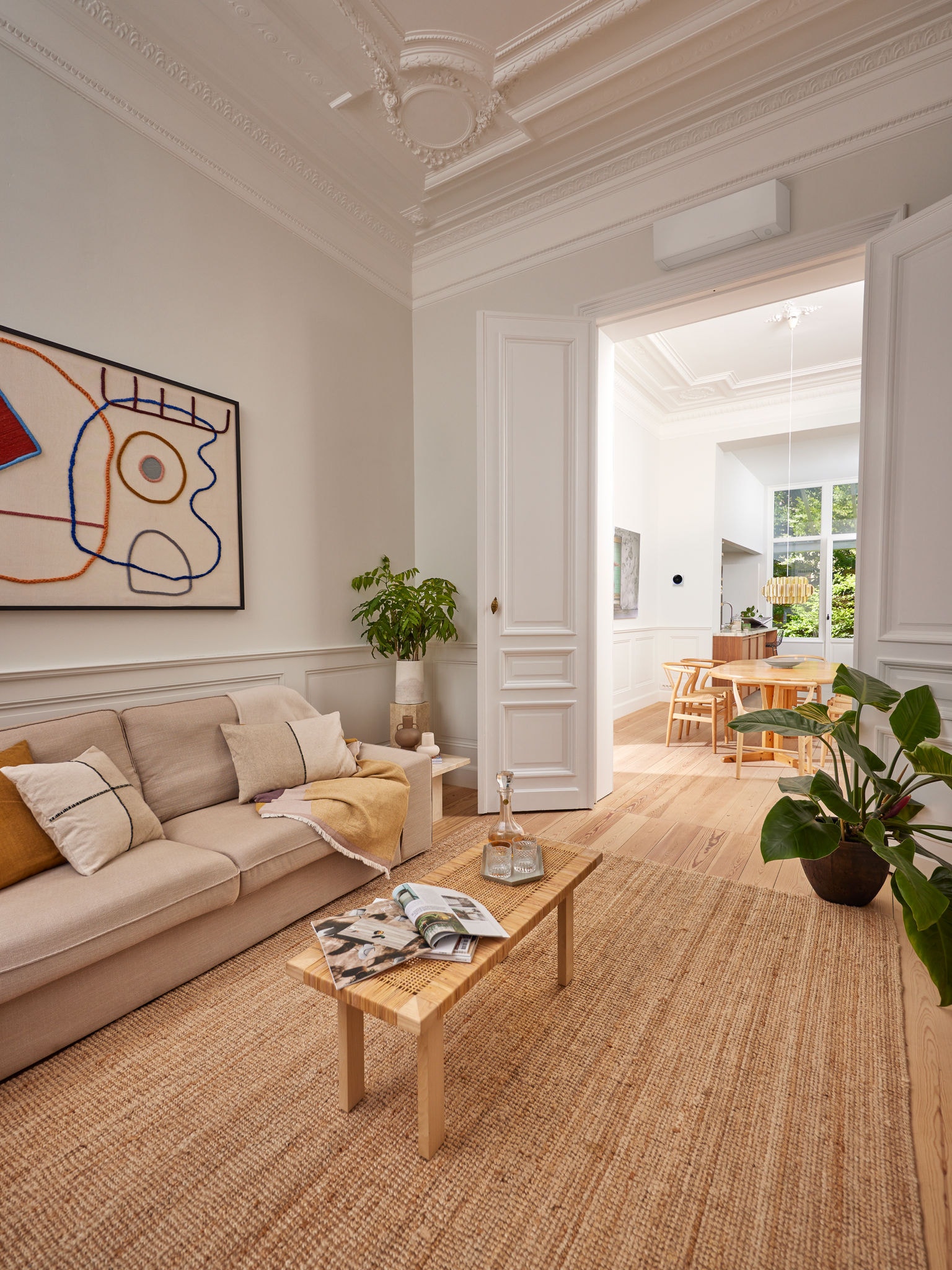 Een elegante woonkamer met een warmtepomp boven de deuropening, om te demonstreren hoe stimuleringsregelingen van de overheid warmtepompen toegankelijker maken voor duurzame verwarming en koeling van woningen