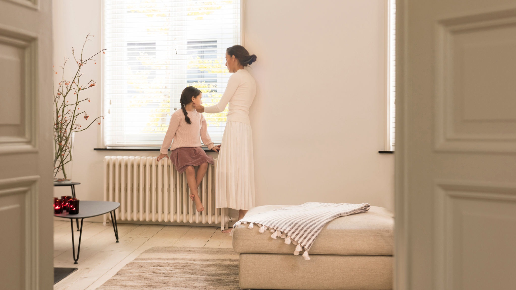 Moeder en dochter kijken uit het raam vanuit hun perfect verwarmde woonkamer