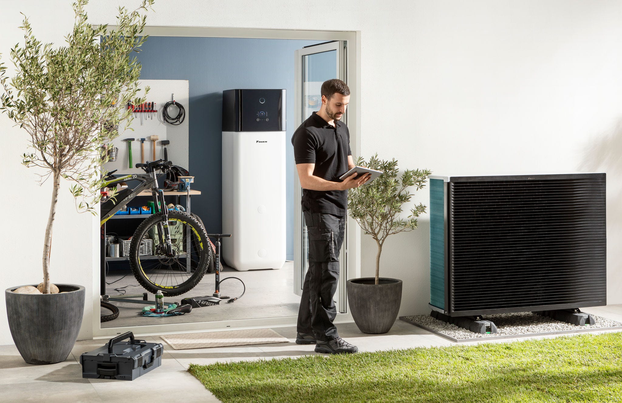 Installateur die buitendeel en warmtapwatertank van luchtwarmtepomp controleert