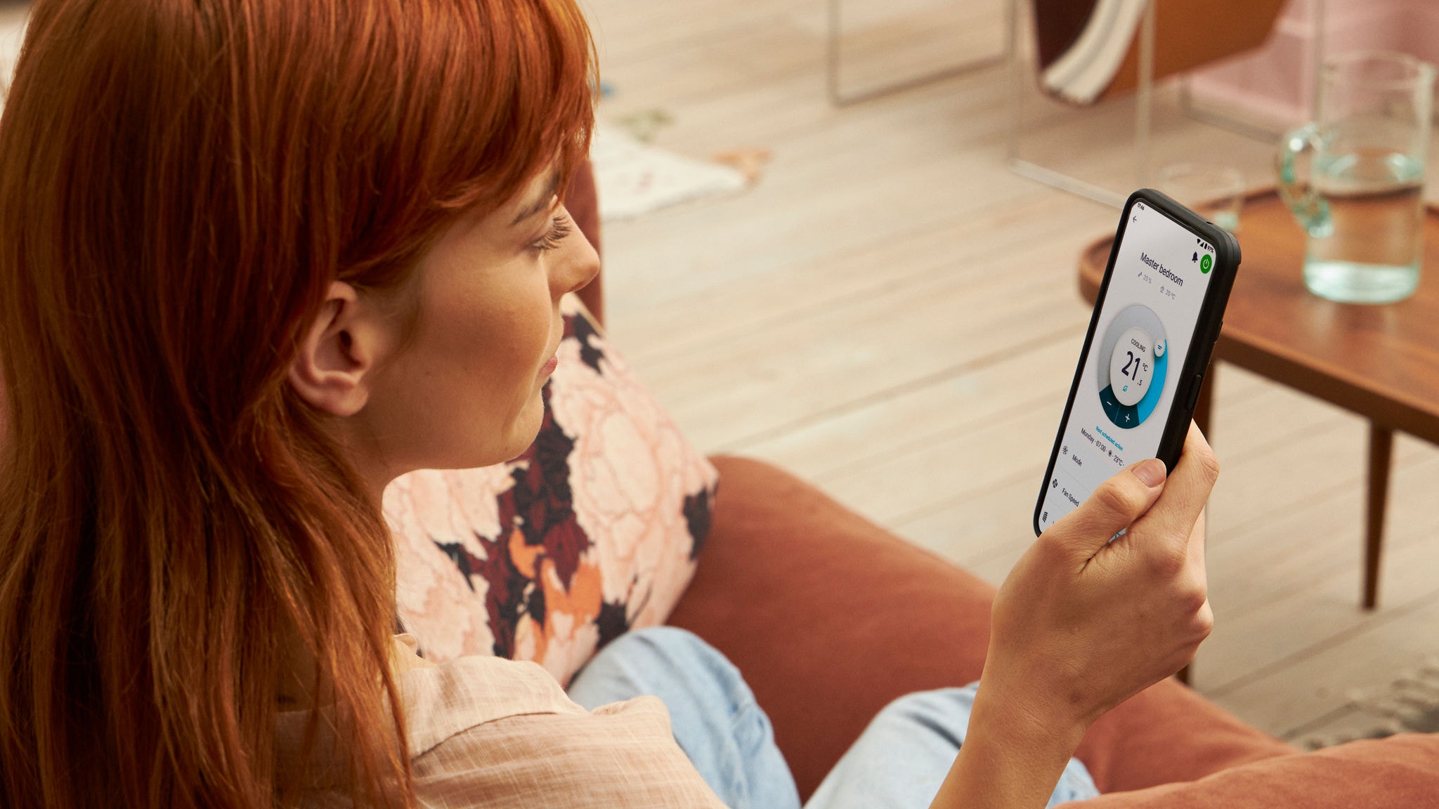 Een vrouw gebruikt de Onecta app om de verwarming te controleren