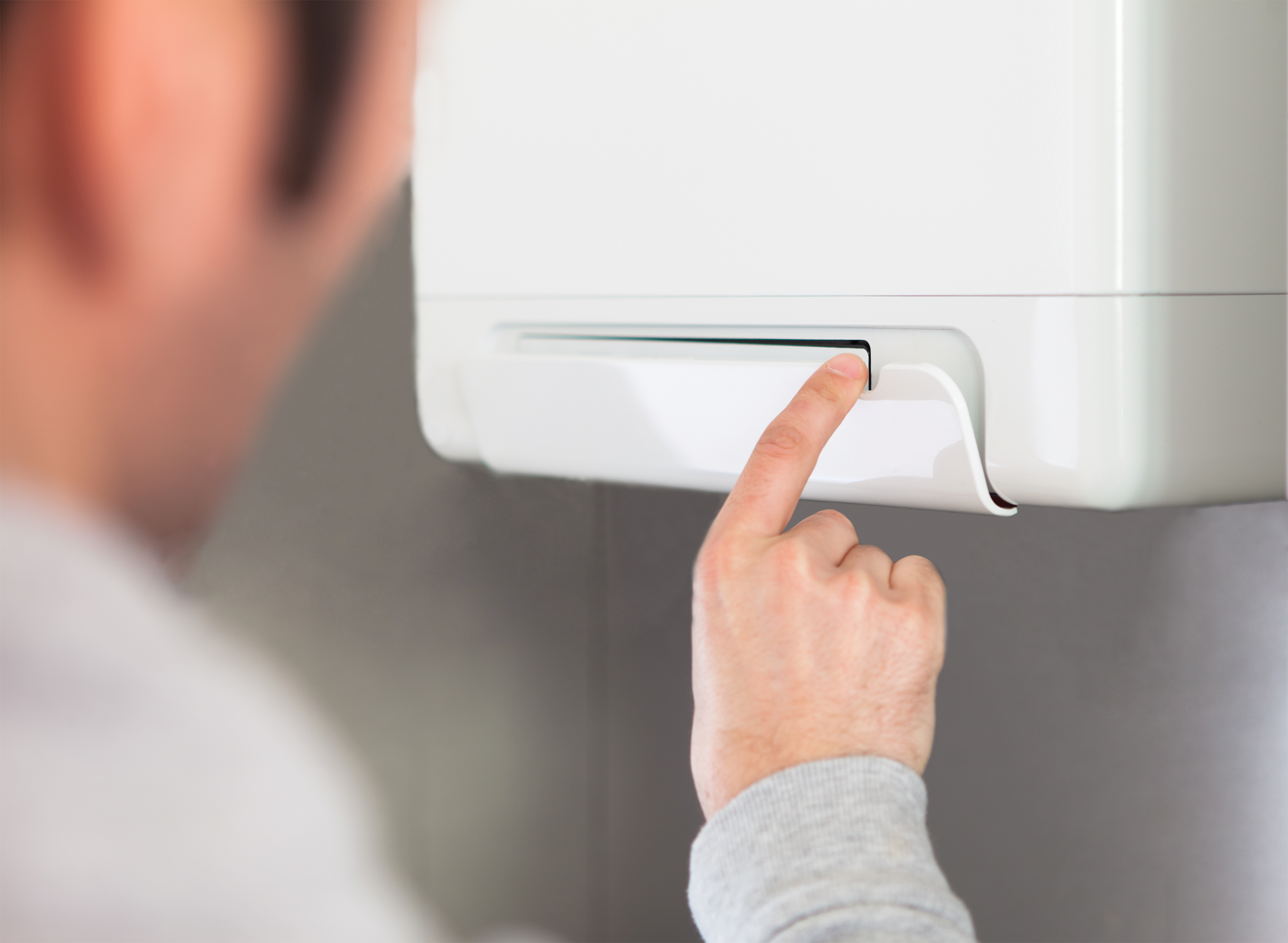 een man klikt op een knopje van de hybride warmtepomp