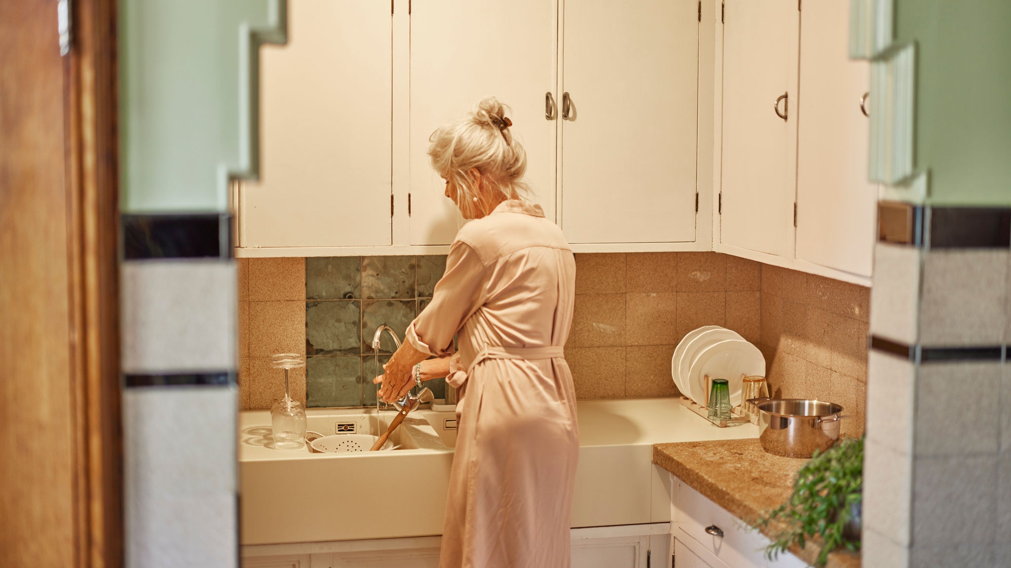 Vrouw die de afwas doet met warm water uit een multi-splitsysteem