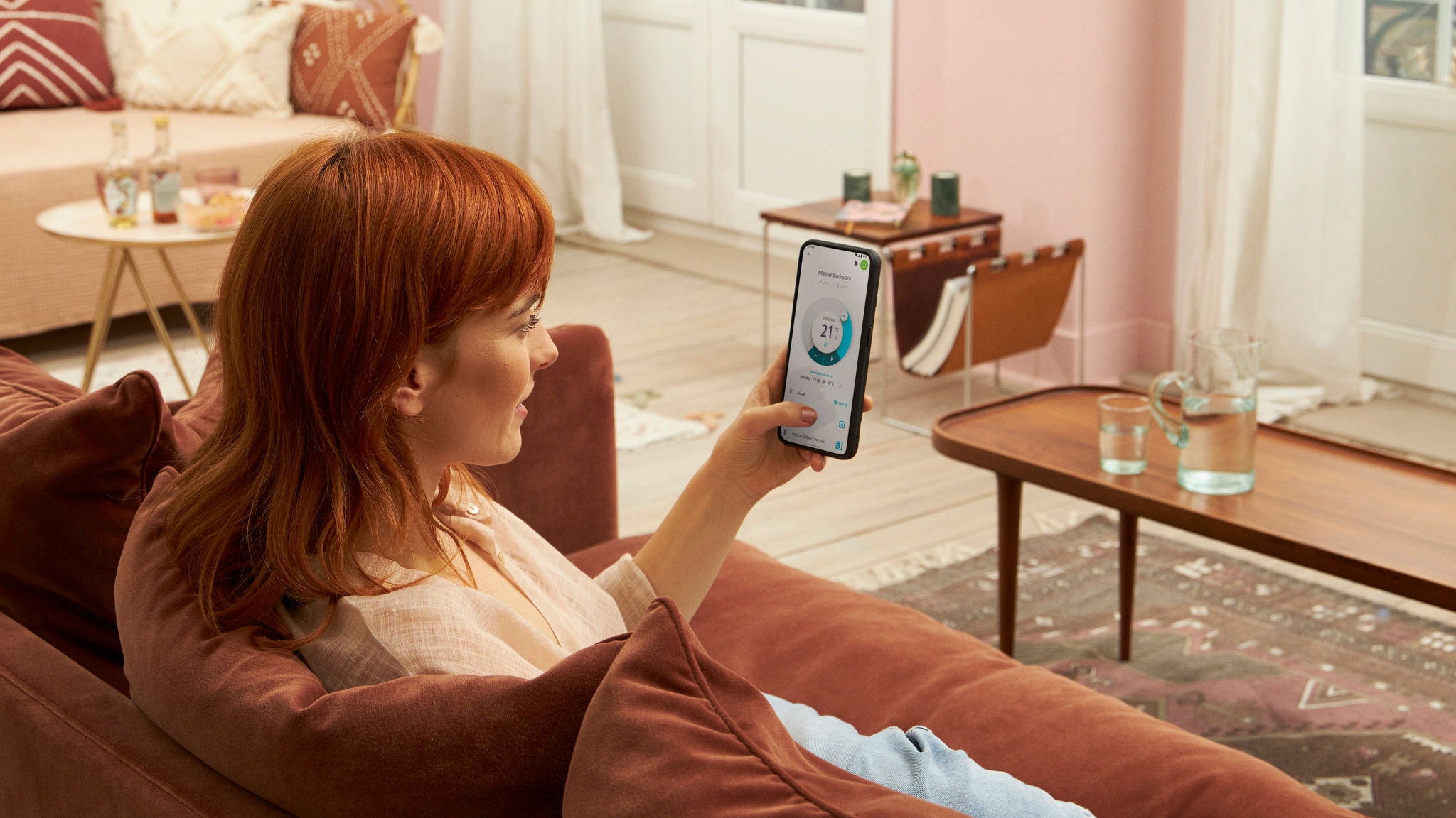 Een vrouw die op de bank zit en de Onecta app gebruikt op haar mobiele telefoon