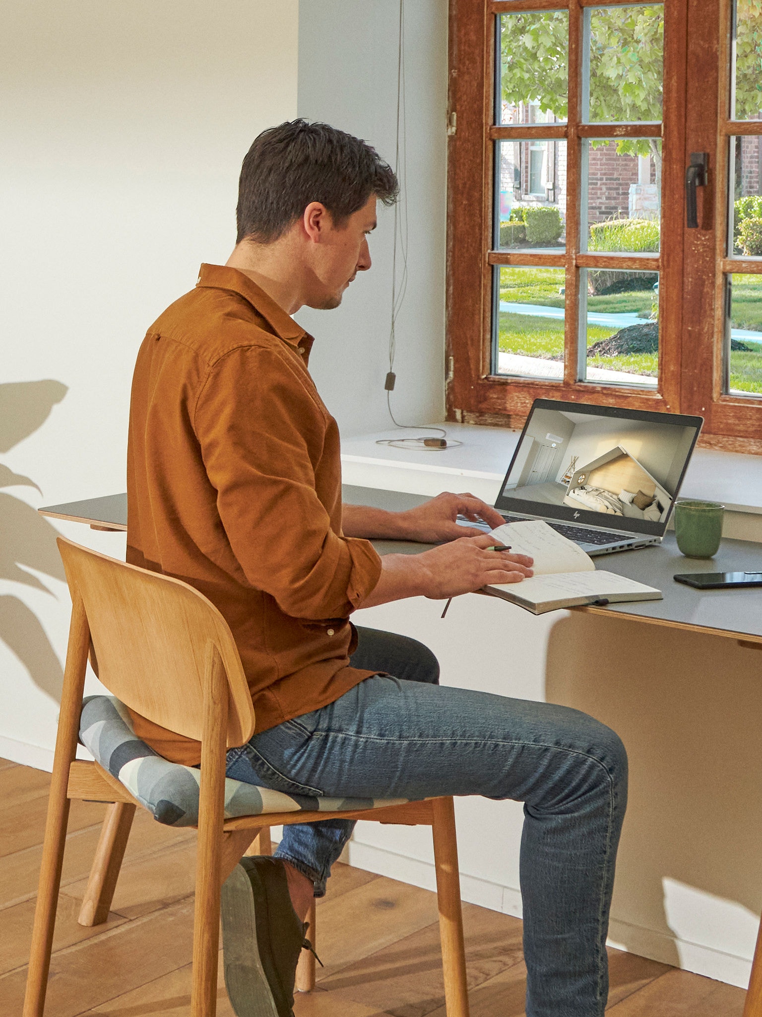 Man zit aan zijn bureau en bekijkt airco's in de Virtuele Showroom op zijn laptop