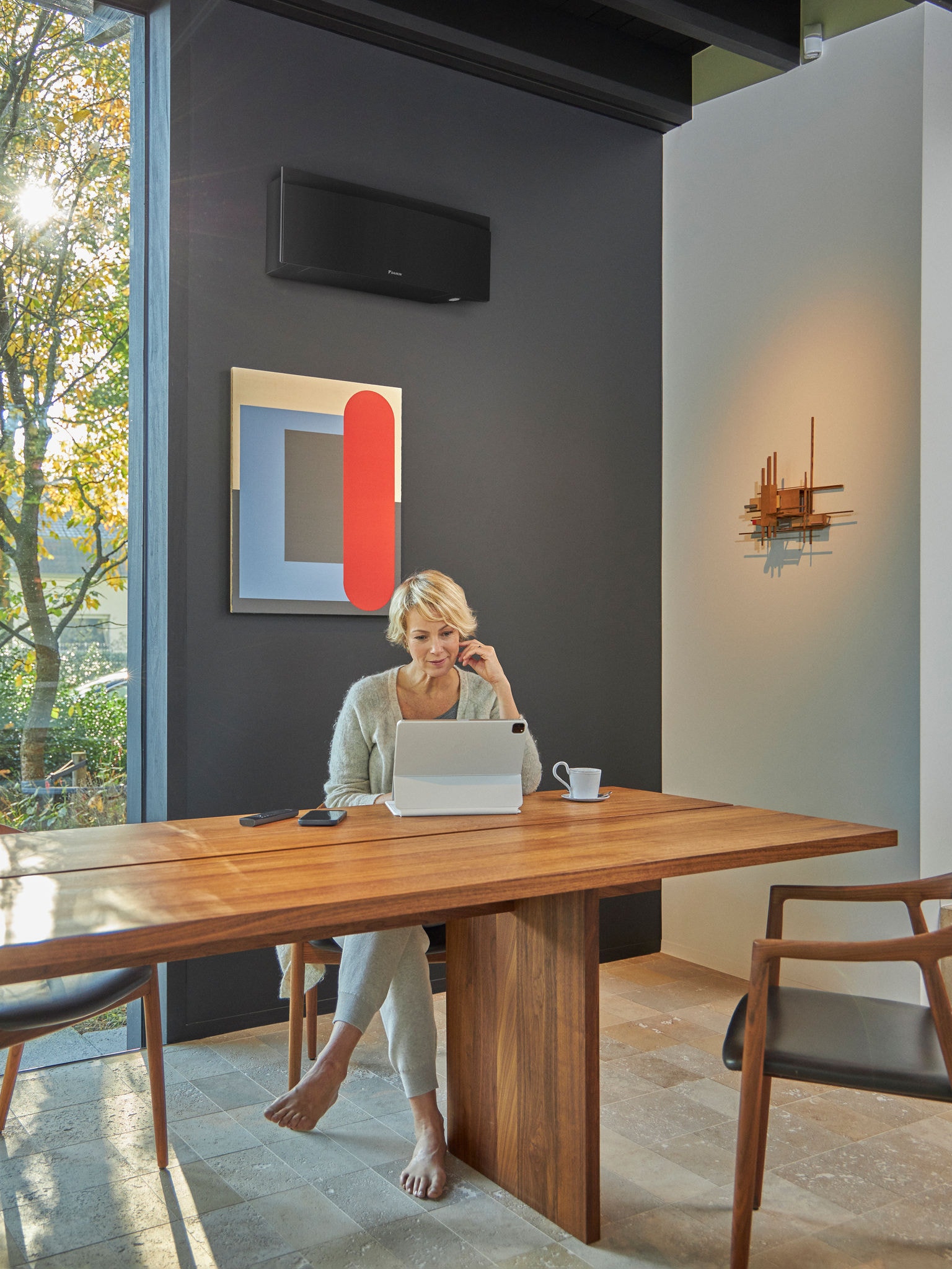 Vrouw die een tablet gebruikt in een eetkamer met wandmodel airconditioner