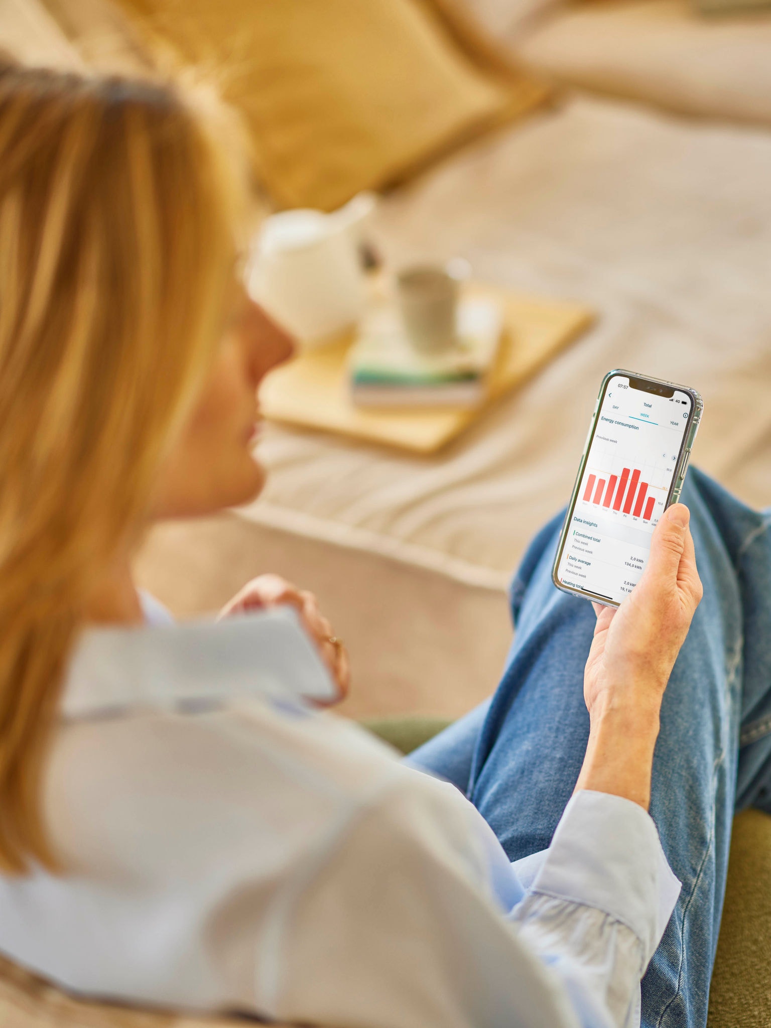 Een blonde vrouw bekijkt haar energieverbruik in een app op haar telefoon
