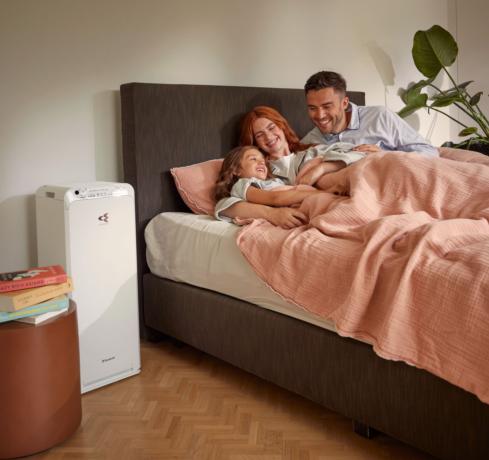 Een stel met kind ontspant in de slaapkamer en geniet van schone lucht met luchtreiniger