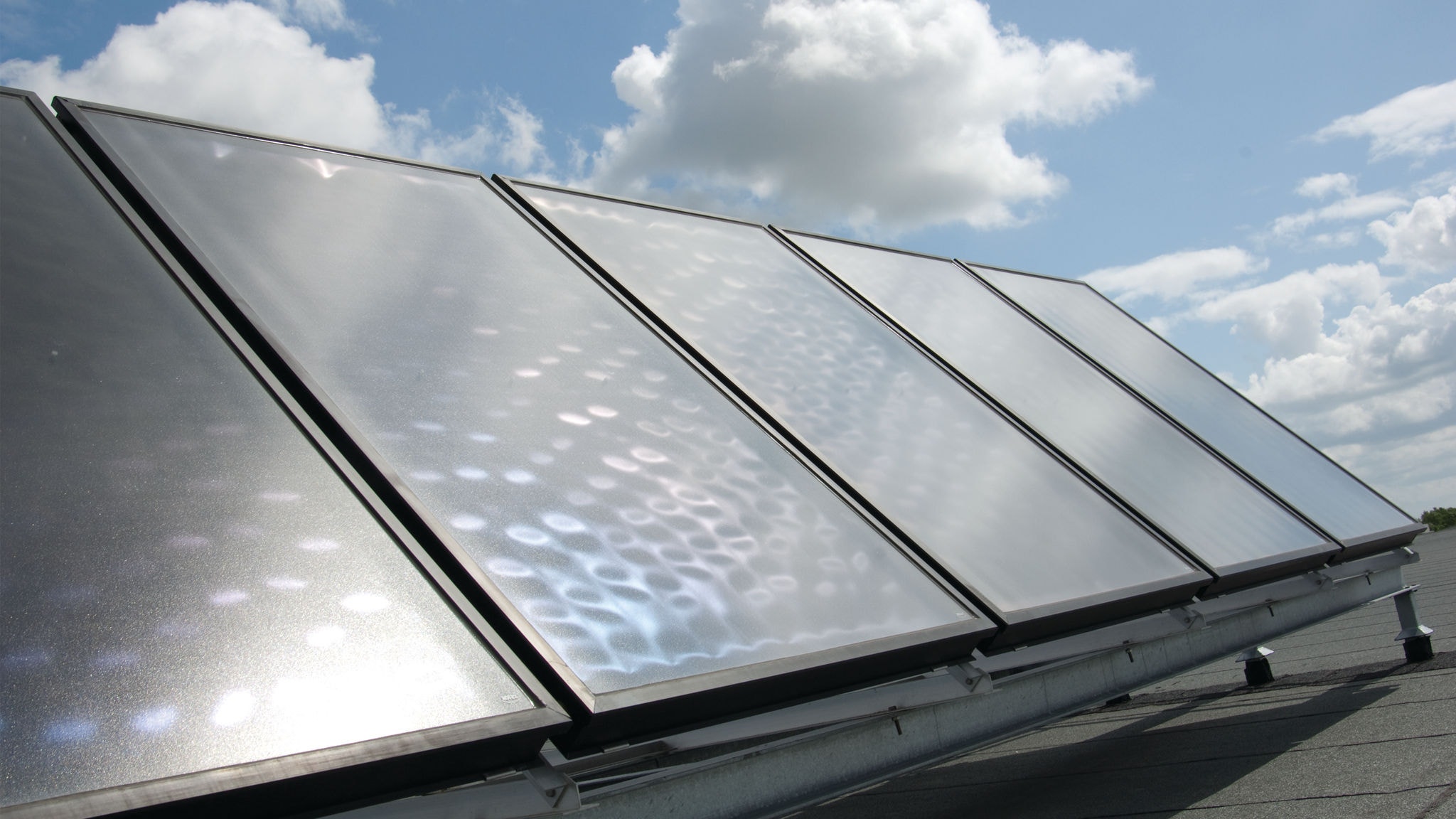 Zonnecollectoren gemonteerd op een dak en gekoppeld aan een Daikin warmtepomp voor synergie en om geld te besparen