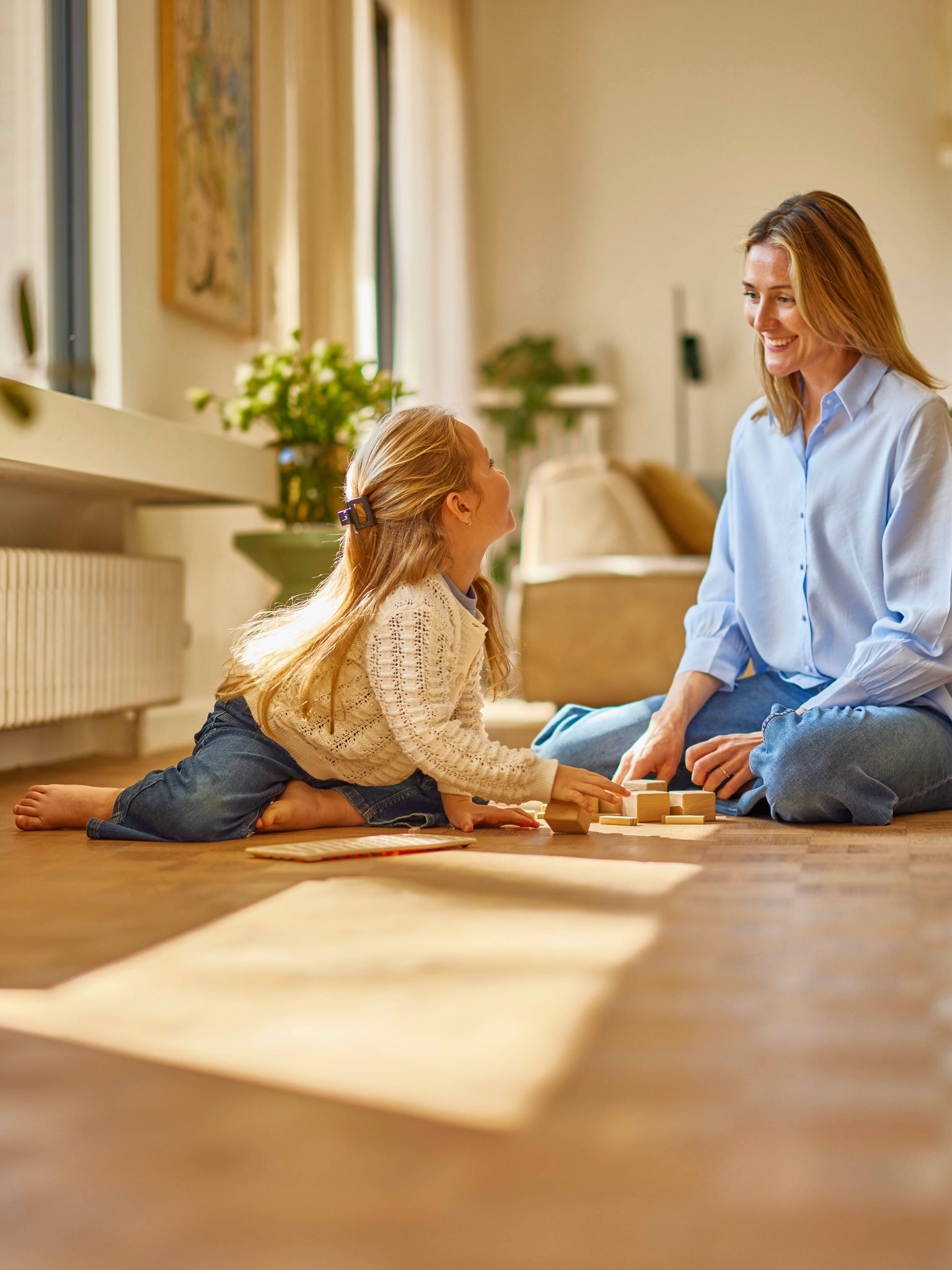Een moeder speelt met haar dochter in een comfortabel verwarmde kamer met een wandradiator