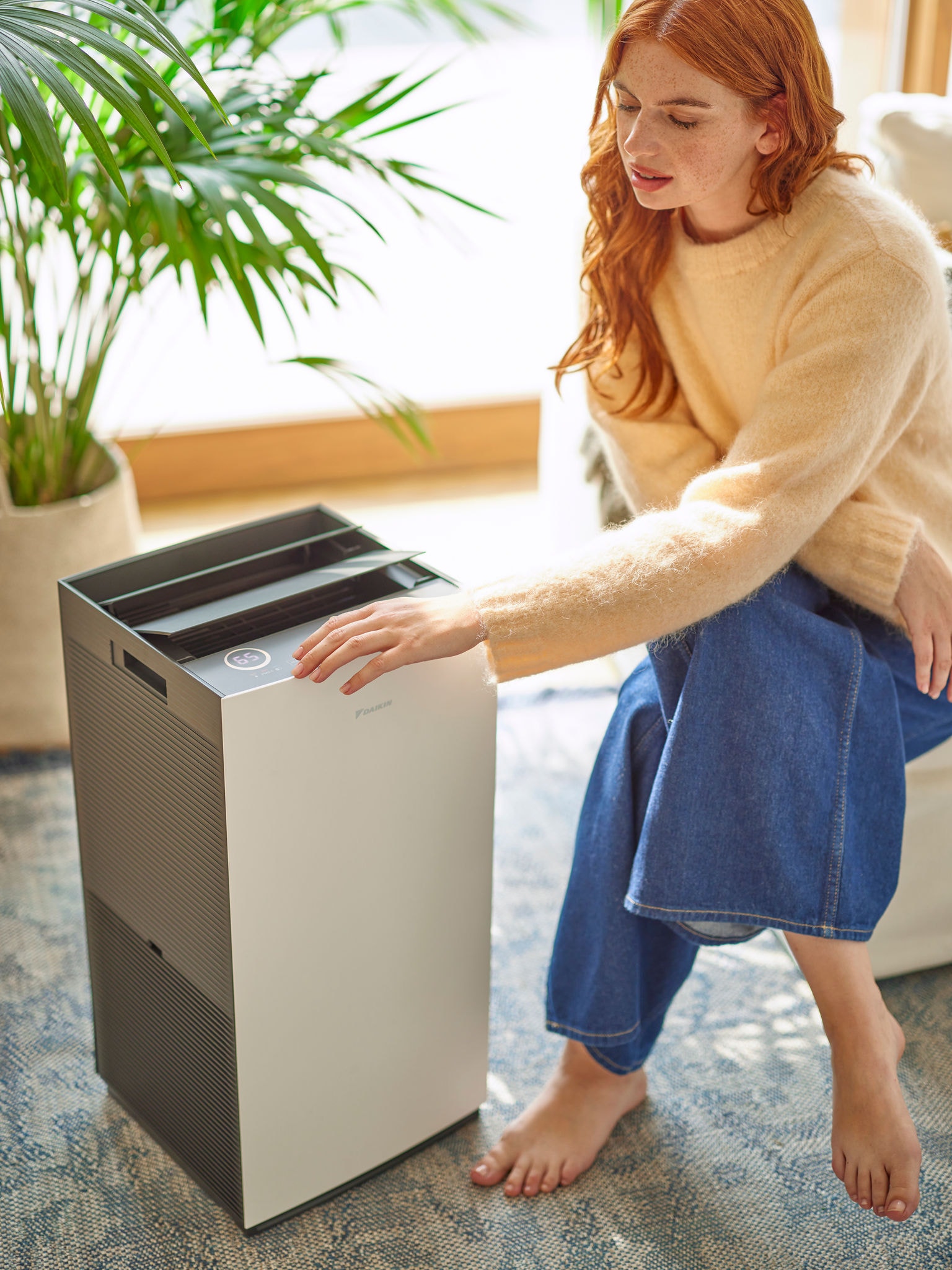 Vrouw in de woonkamer die de regeling van een Daikin luchtreiniger aanpast