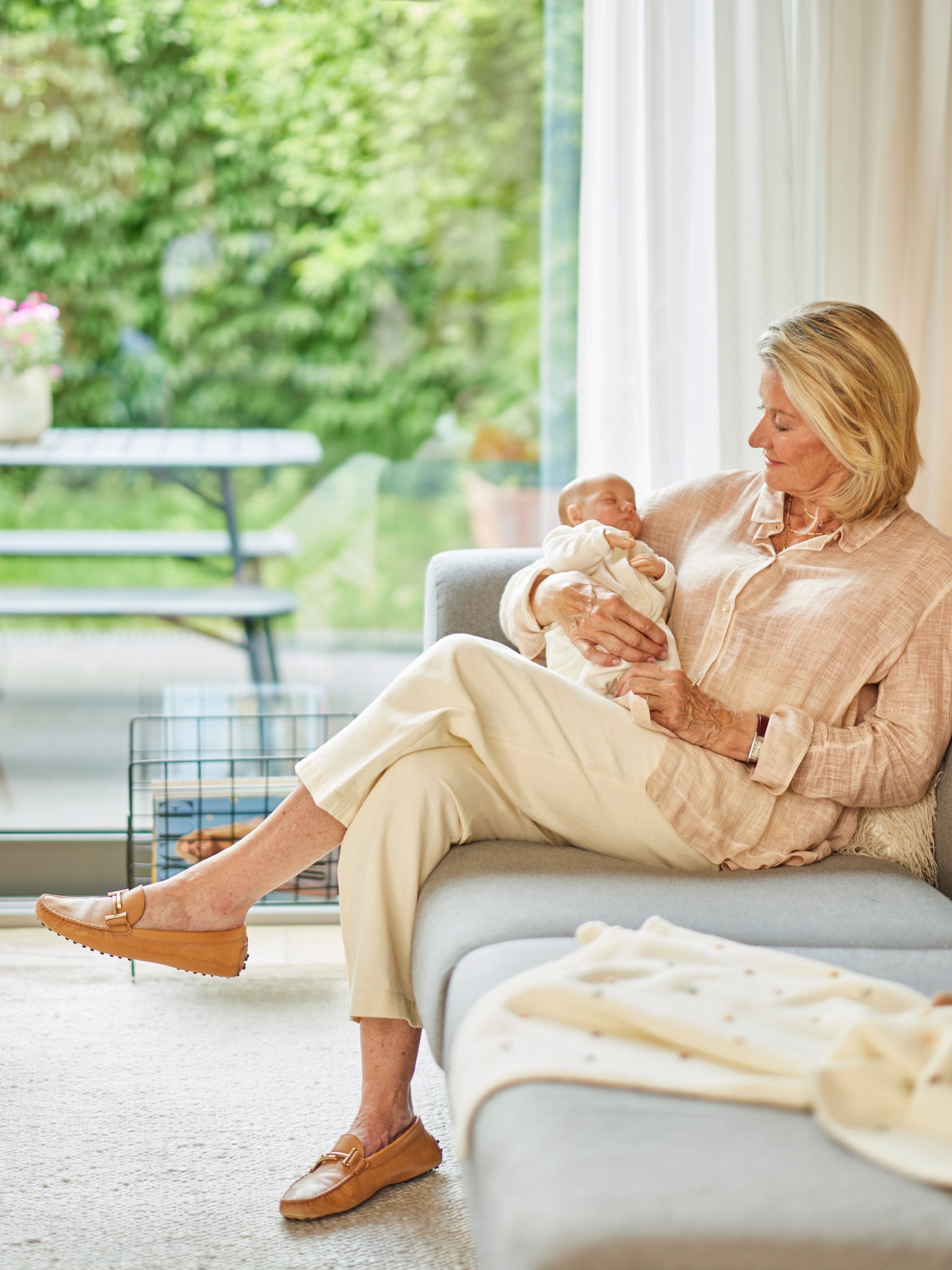 Vrouw die een baby vasthoudt terwijl ze op een bank zitten in een aangenaam verwarmde ruimte.
