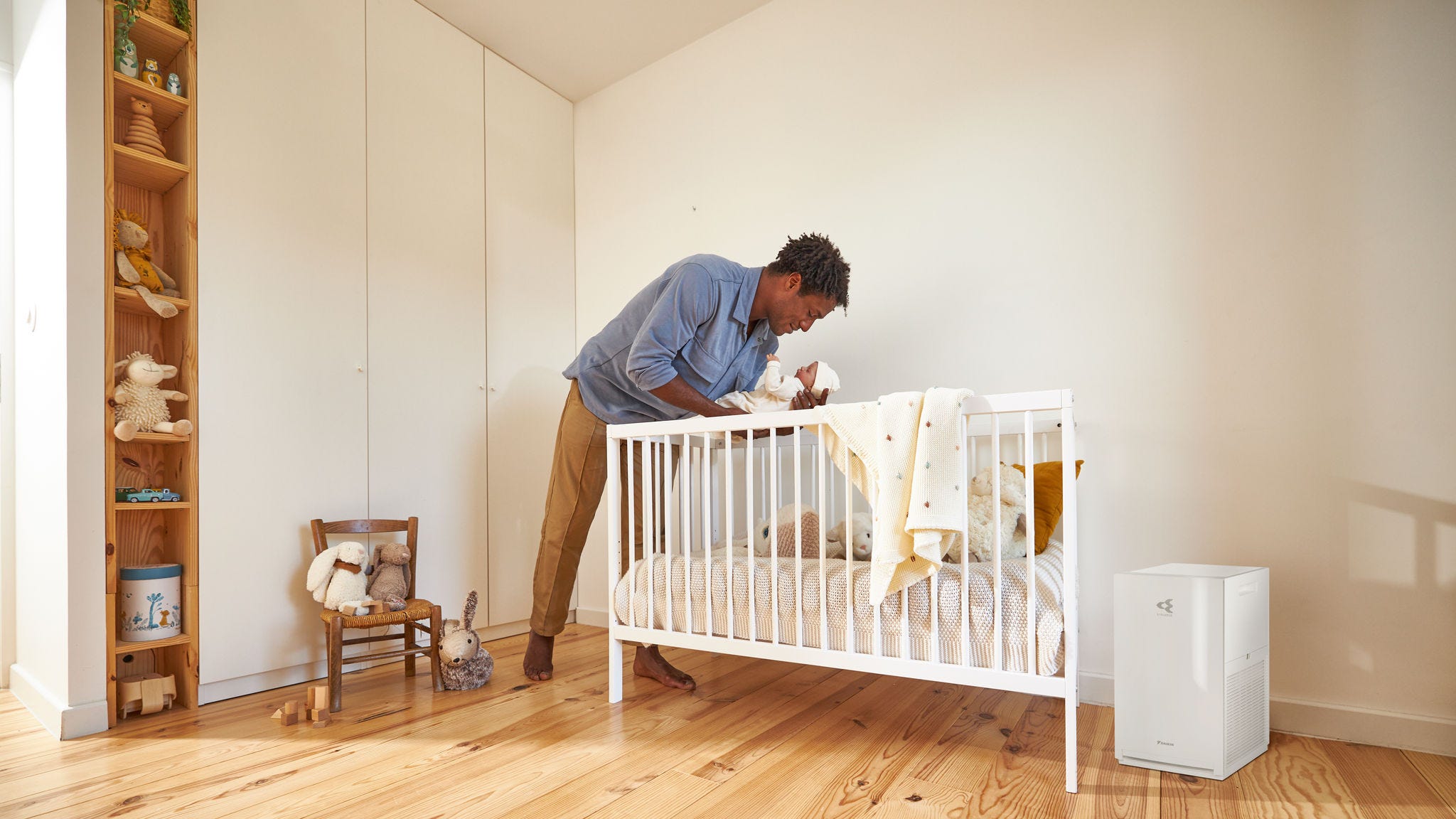 Vader die zijn baby instopt in een rustige babykamer met een luchtreiniger