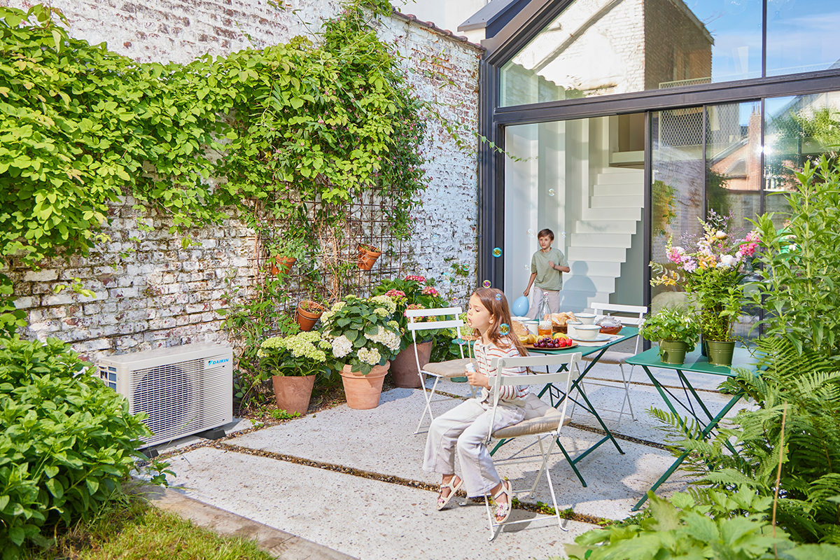 Kinderen die buiten knikkeren op een tuinterras naast een warmtepomp