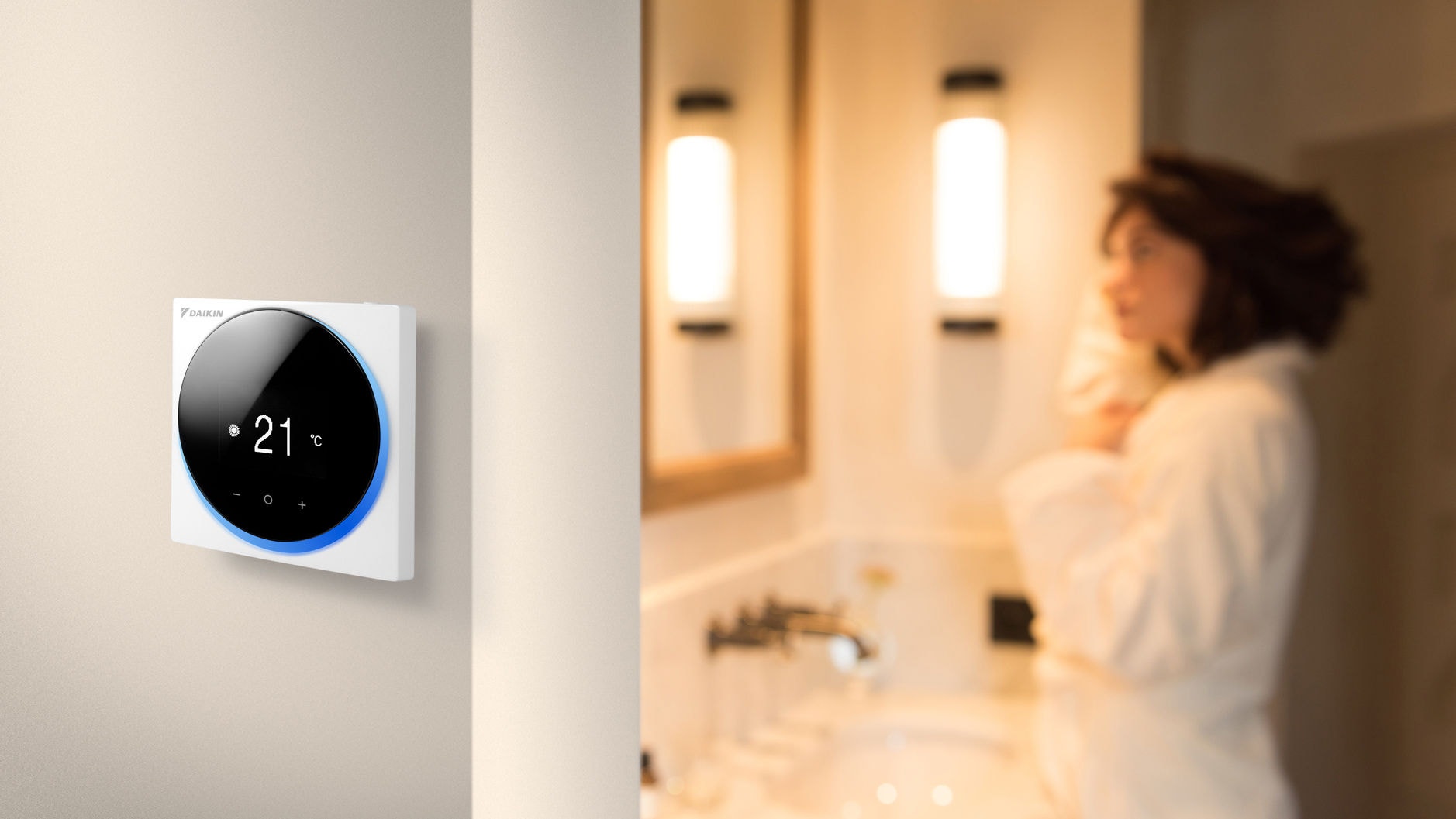 Een vrouw staat in een badkamer naast een kamer met een wandgemonteerde compacte bedrade kamerthermostaat