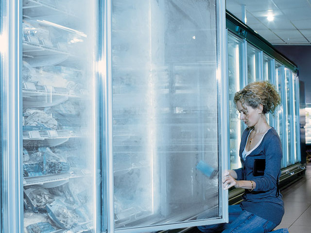 Vrouw maakt diepvriezers schoon in een supermarkt